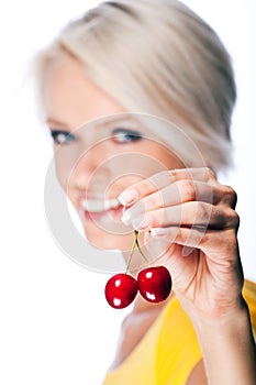 Beautiful blond woman holding two ripe cherries