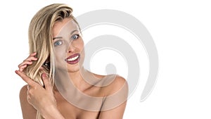 Beautiful blond woman with long hair touching her hair on whie background. Perfect smile. Copy space