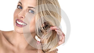 Beautiful blond woman with long hair touching her hair on whie background. Perfect smile. Stomatology concept