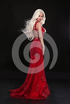 Beautiful blond woman in red dress isolated on black background.