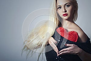 Beautiful Blond Woman with Red Heart. Beauty Girl. Show Love Symbol. Valentine's Day. Black Dress