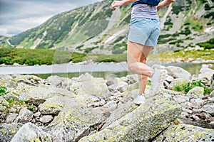 Beautiful blond woman is running in the mountains on rocks and stones.