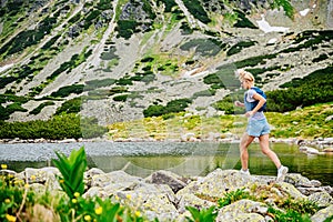 Beautiful blond woman is running in the mountains on rocks and stones.