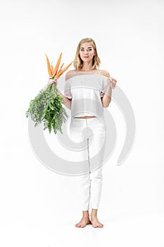 Beautiful blond woman showing rabbit and holding fresh carrot with green leaves on white background. Health and Diet