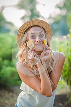 Beautiful blond woman standing on the street with a slice of lemon.