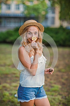 Beautiful blond woman standing on the street with a slice of lemon.