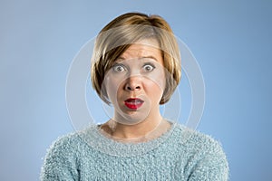 Beautiful blond woman in surprise and shock face expression expressing anxiety and fear