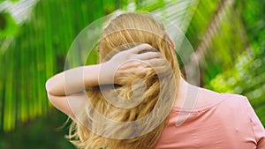 Beautiful blond woman touches her hair in nature. back view. hair treatment concept