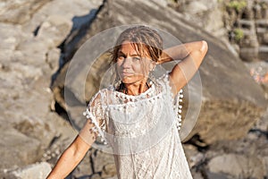 beautiful blond woman wearing a white shirt posing on a rock