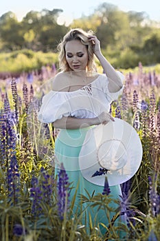 beautiful blond woman in white dress on lupin field summer background close up portrait