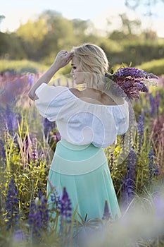 beautiful blond woman in white dress on lupin field summer background close up portrait