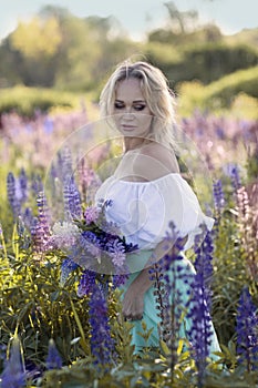 beautiful blond woman in white dress on lupin field summer background close up portrait