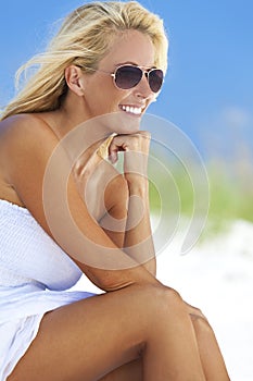 Beautiful Blond Woman in White Dress and Sunglasses At Beach