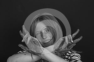 Beautiful blond young girl with freckles and hands painted in colorful paints indoors , closeup portrait, black and white