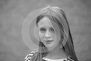 Beautiful blond young girl with freckles outdoors on wall background, closeup portrait, black and white