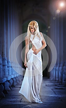 Beautiful blonde angel with white light wings and white veil posing outdoor