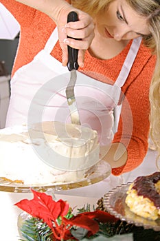 Beautiful blonde in an apron frosting a cake