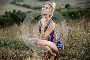 Beautiful blonde with beautiful eyes in blue overalls in nature, sunset sun