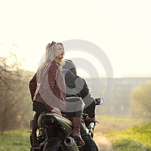 Beautiful blonde with a biker posing near a sports bike.