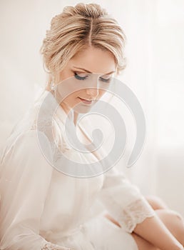 Beautiful blonde bride with stylish make-up in white dress.Morning bride