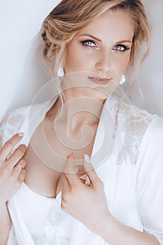 Beautiful blonde bride with stylish make-up in white dress.Morning bride