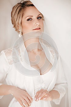 Beautiful blonde bride with stylish make-up in white dress.Morning bride