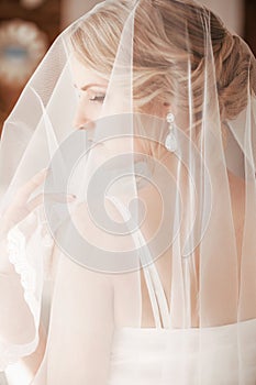 Beautiful blonde bride with stylish make-up in white dress.Morning bride