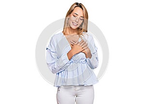 Beautiful blonde business woman wearing casual clothes smiling with hands on chest with closed eyes and grateful gesture on face