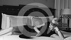 Beautiful blonde business woman wearing skinny short dress jewelry sunglasses luxury hotel bed room relax rest fashion trend