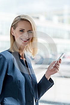 beautiful blonde businesswoman using smartphone and smiling