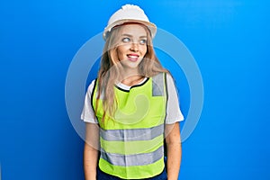 Beautiful blonde caucasian woman wearing architect hardhat looking to side, relax profile pose with natural face and confident