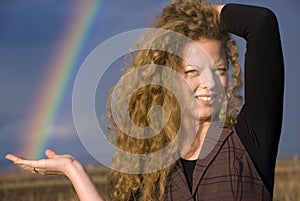 Beautiful blonde curly girl holding a rainbow