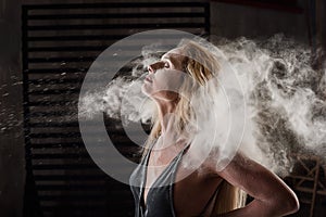 Beautiful blonde dancing in clouds of flour. Woman throws flour into the air