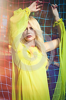 Beautiful blonde fashion woman in long elegant yellow dress pose in amusement park summer