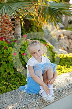 Beautiful blonde girl 5 years old in a blue skirt on background