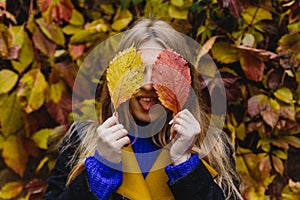 A beautiful blonde girl in a coat walks in the Park