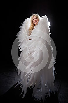 A beautiful blonde girl with curly hair and white wings looks like an nice angel