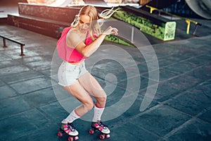 Beautiful blonde girl is doing some tricks during rollerblading. She is standing in a squat position and looking down