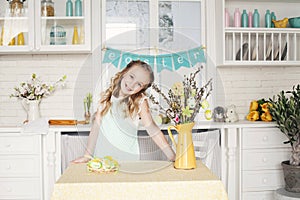 Beautiful blonde girl in floral wreath on white kitchen background preparing Easter cakes. Easter concept. Easter card