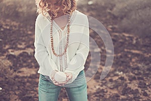 Beautiful blonde girl holding sea shell on hands for nature and environemnt concept - protect earth`s day message - casual chic