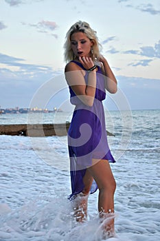 Beautiful blonde girl in a light dress on the shore of the troubled sea