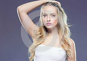 Beautiful blonde girl with long curly hair over purple backgroun