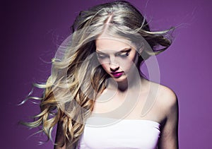 Beautiful blonde girl with long curly hair over purple background