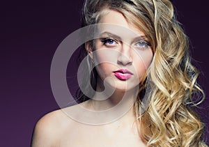 Beautiful blonde girl with long curly hair over purple background