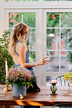 Girl in blue dress standing with glass of wine