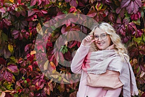 A beautiful blonde girl in a pink coat walks in the Park