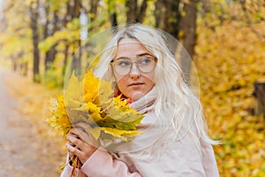 A beautiful blonde girl in a pink coat walks in the Park