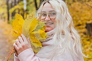 A beautiful blonde girl in a pink coat walks in the Park