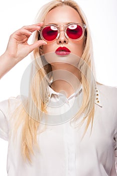 Beautiful blonde girl in pink glasses and shirt. Beauty face. Isolated on white background.