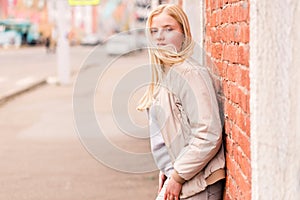 Beautiful blonde girl posing near a brick wall